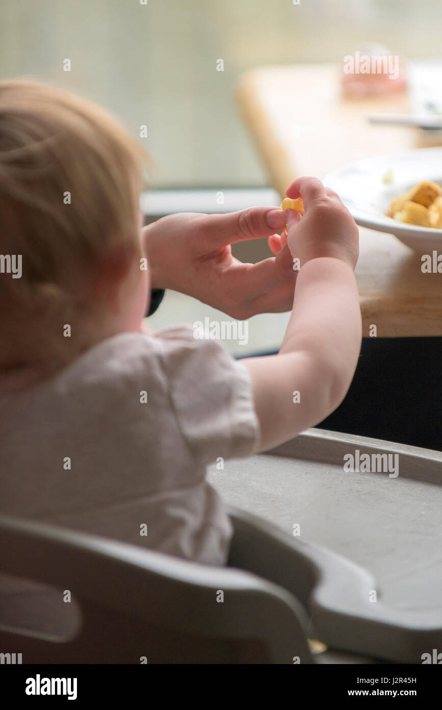 Il Toddler; Fed cibo; mani; mangiare; ristorante interno; i clienti bambino affamato Foto Stock