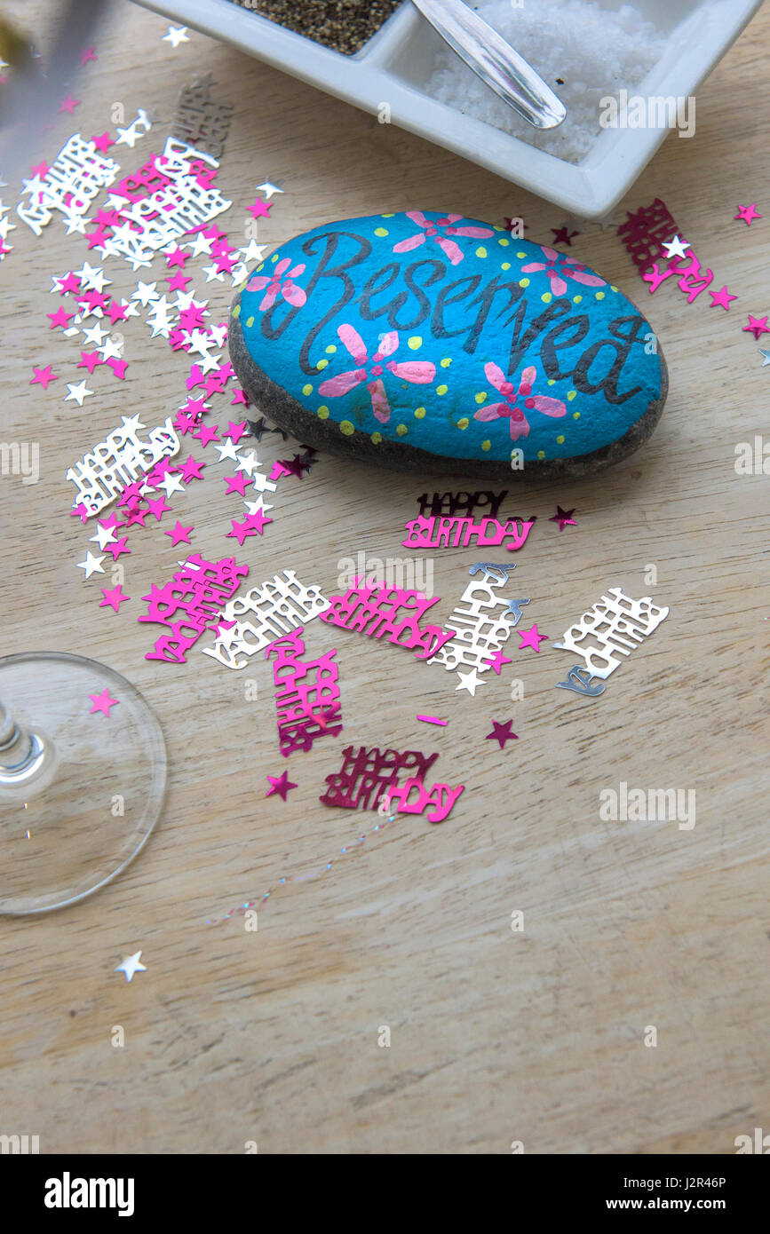 Ristorante interno tavolo riservato segno dipinto pebble tabella decorazioni feste di compleanno piuttosto colorato colorato Foto Stock