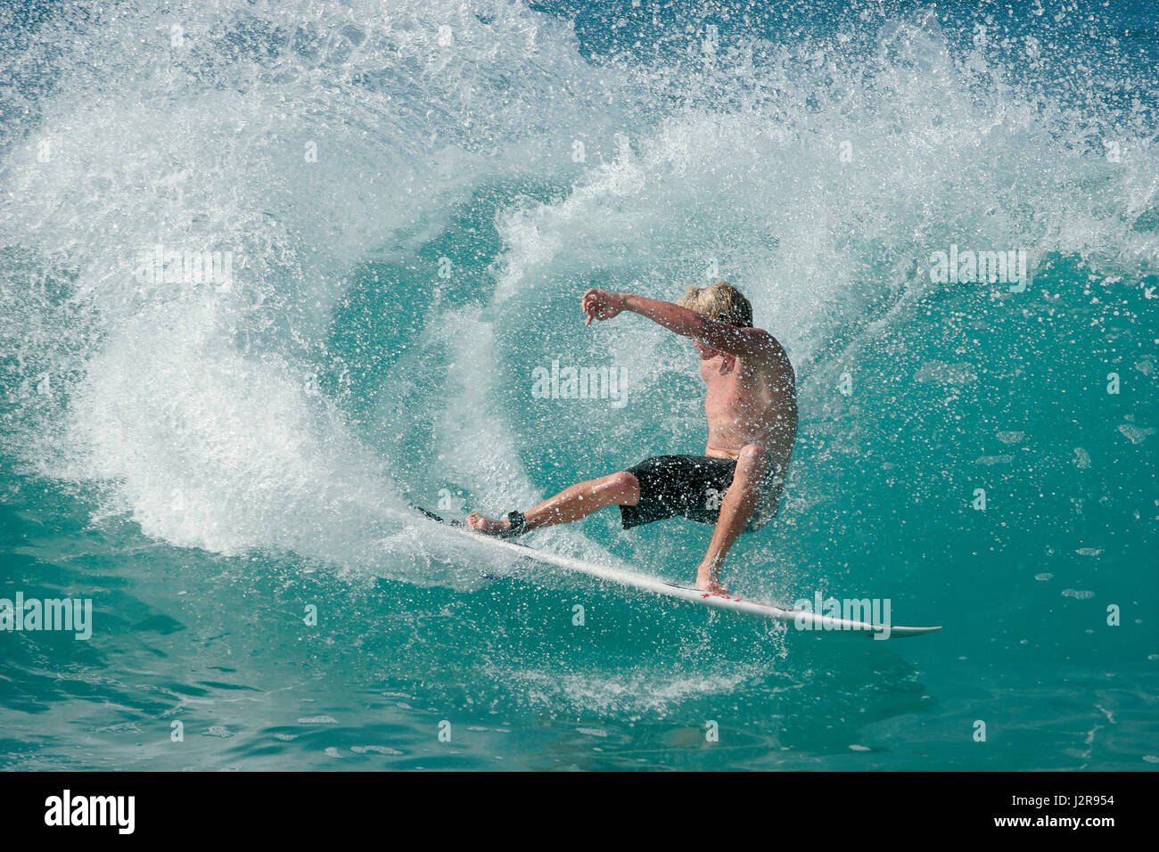 Un surfista maschio esegue un radicale spostare su un splendido oceano onda. Foto Stock