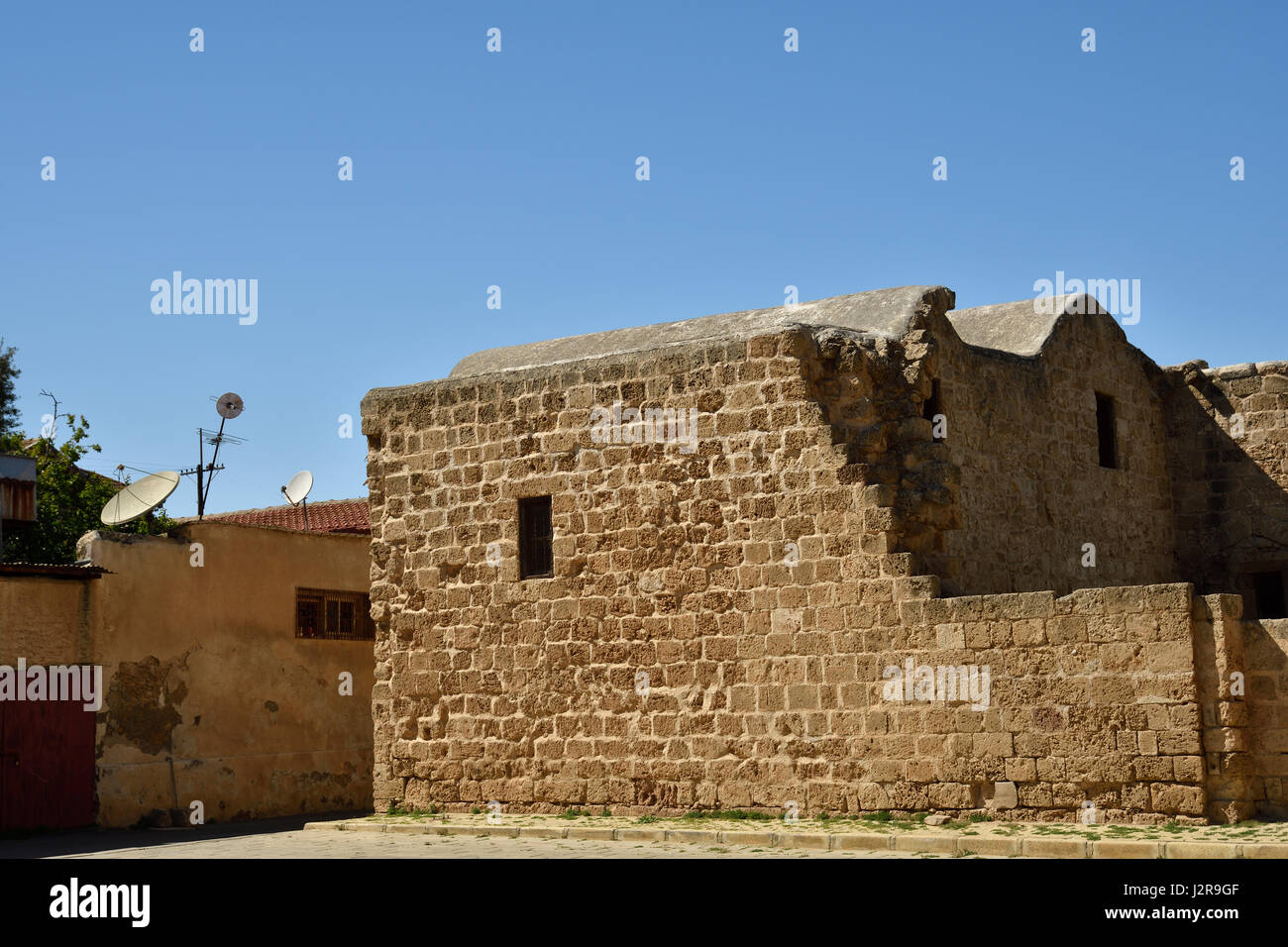 Vecchia casa con antenna parabolica vicino ad una rovina con cielo blu sullo sfondo, immagine dalla parte settentrionale di Cipro. Foto Stock
