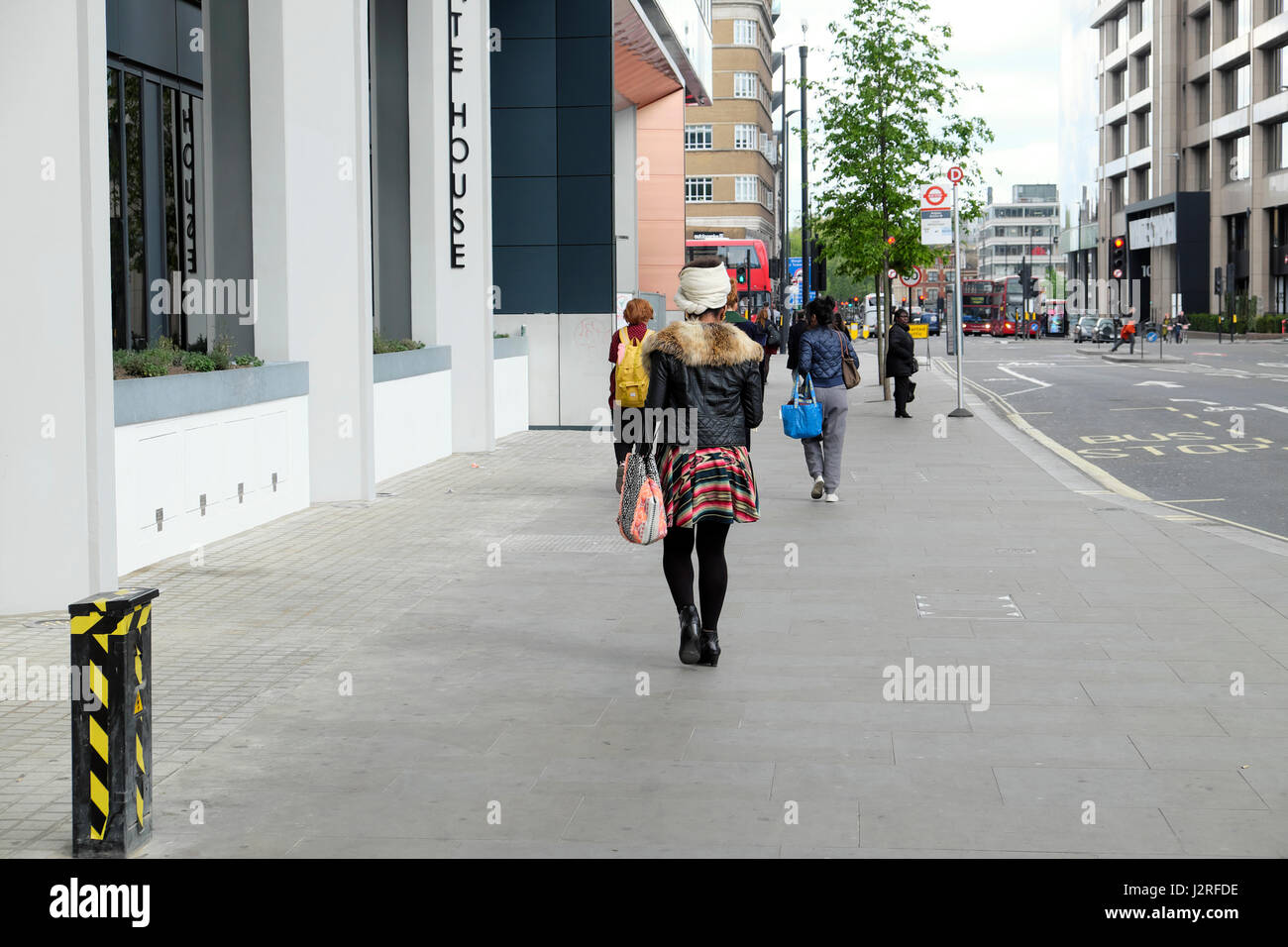 Moda giovane donna a piedi lungo Aldgate High Street in direzione di Whitechapel di East London EC3 UK KATHY DEWITT Foto Stock