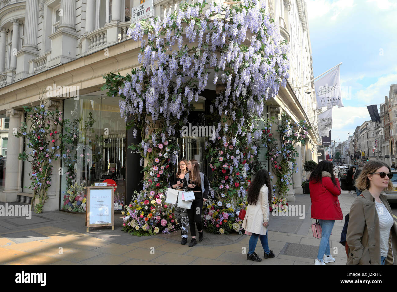 Fiori artificiali con il glicine salutare gli acquirenti all'entrata di Fenwick's department store al Brook St e New Bond Street, Londra UK KATHY DEWITT Foto Stock