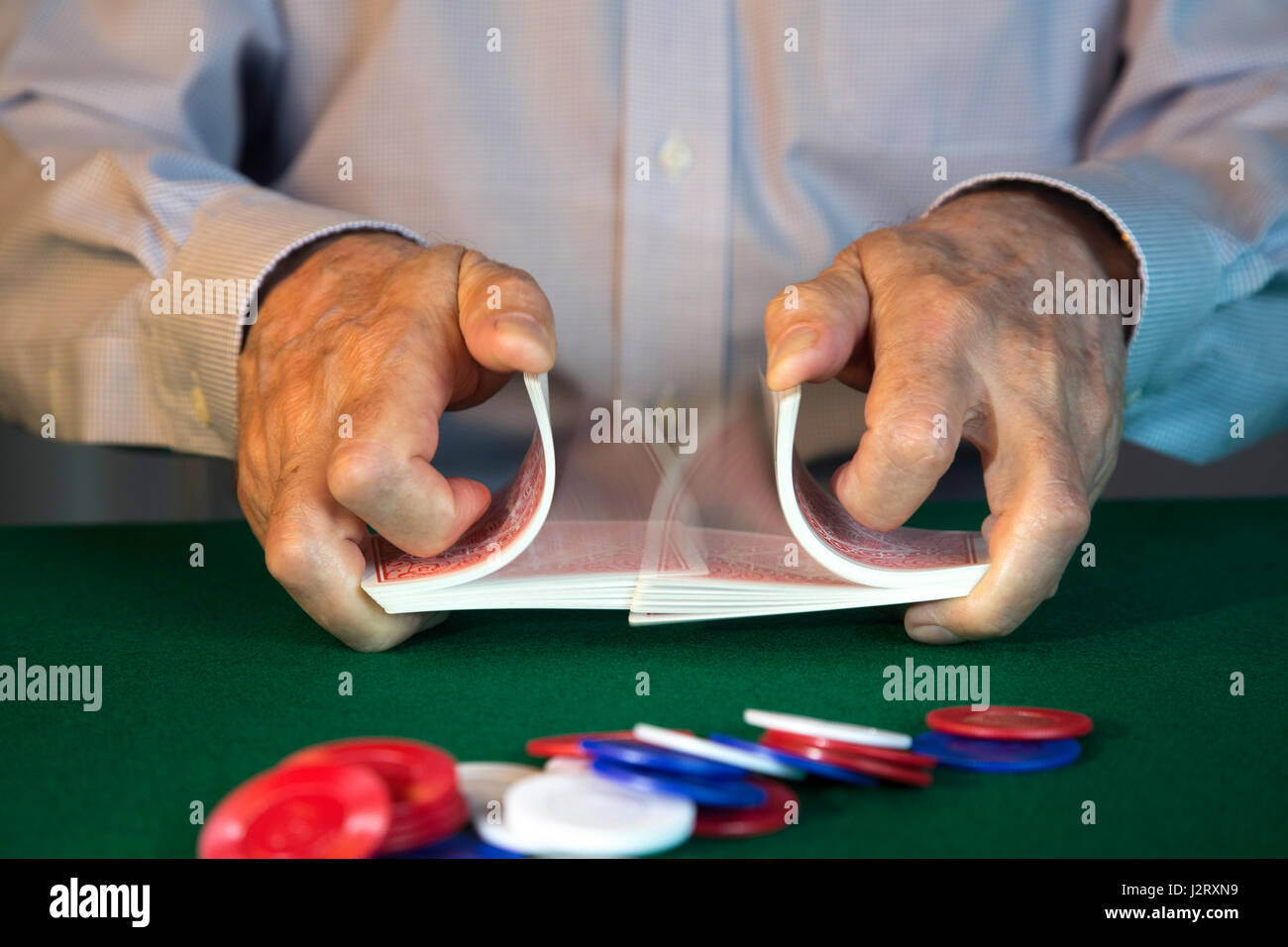 L'uomo rimescolare le carte di fronte al gioco di Poker Foto Stock