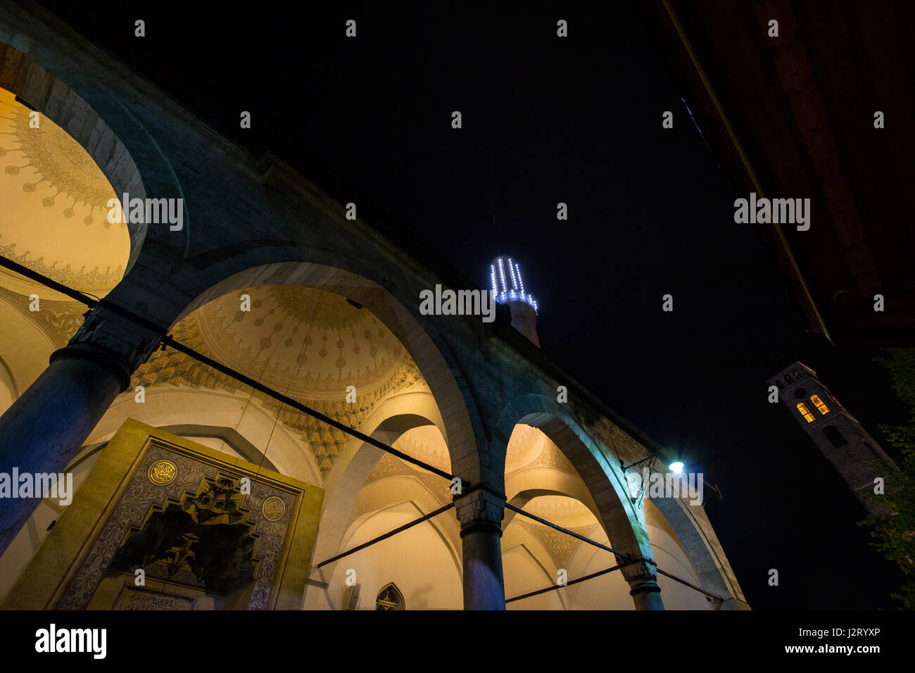 Gazi Husrev moschea Begova a Sarajevo in serata. Il Sarajevo bazar di clock tower possono essere visti sullo sfondo. La moschea è uno dei principali terreni Foto Stock