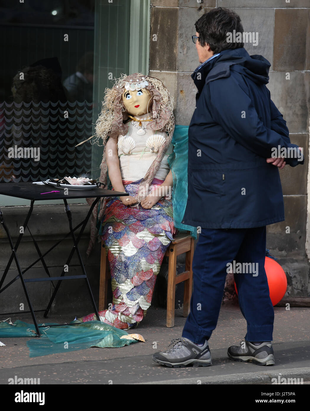 Una donna cammina passato uno spaventapasseri sul display durante la Elie Spaventapasseri festival di Elie, Scozia. Foto Stock