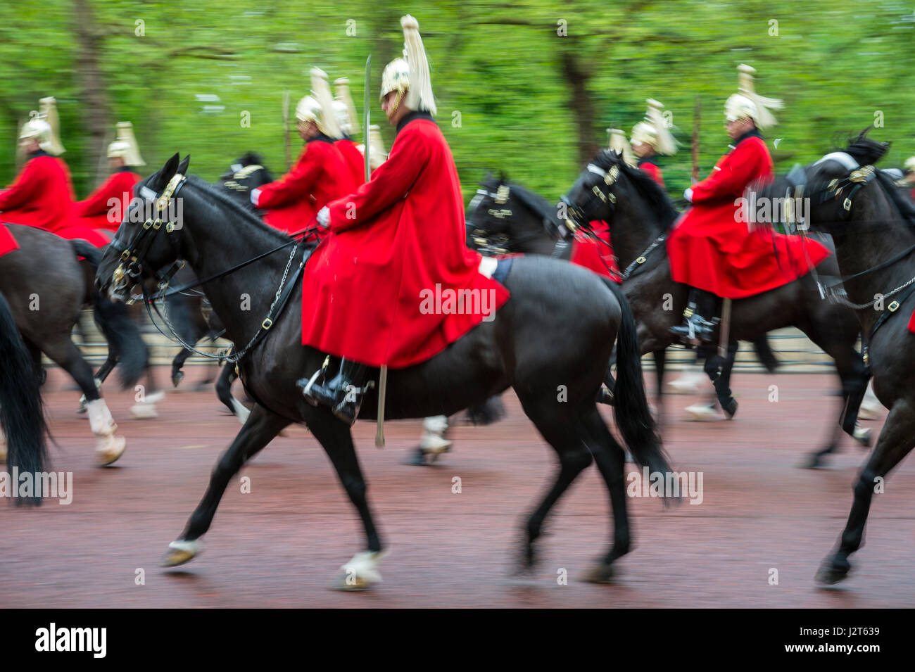 Londra - 18 Maggio 2016: montato reggimento della regina guardie in rosso cappotti passano in motion blur sul Mall durante un royal Trooping la processione del colore. Foto Stock