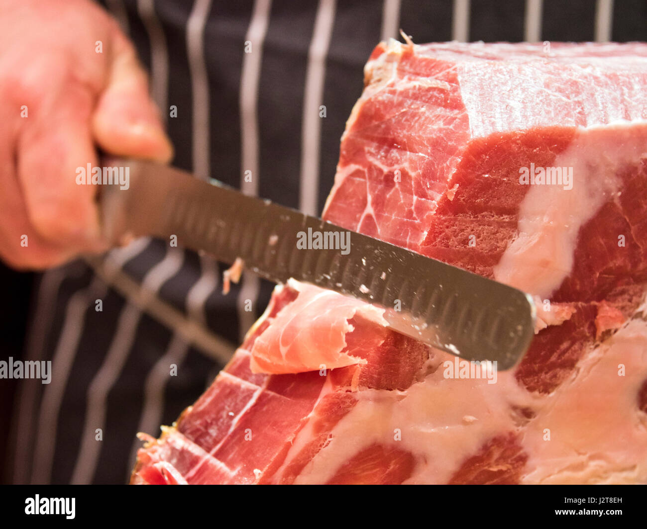 Chiudere orizzontale di un macellaio di tranciatura di un prosciutto Serrano. Foto Stock