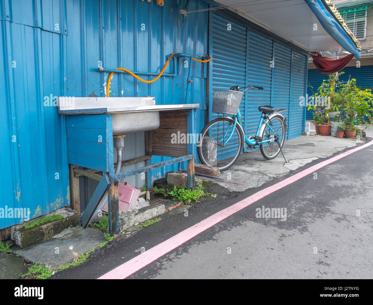 Taipei, Taiwan - Ottobre 08, 2016: biciclette blu e un lavandino con un blu porta di garage in uno sfondo per le strade di Taipei Foto Stock