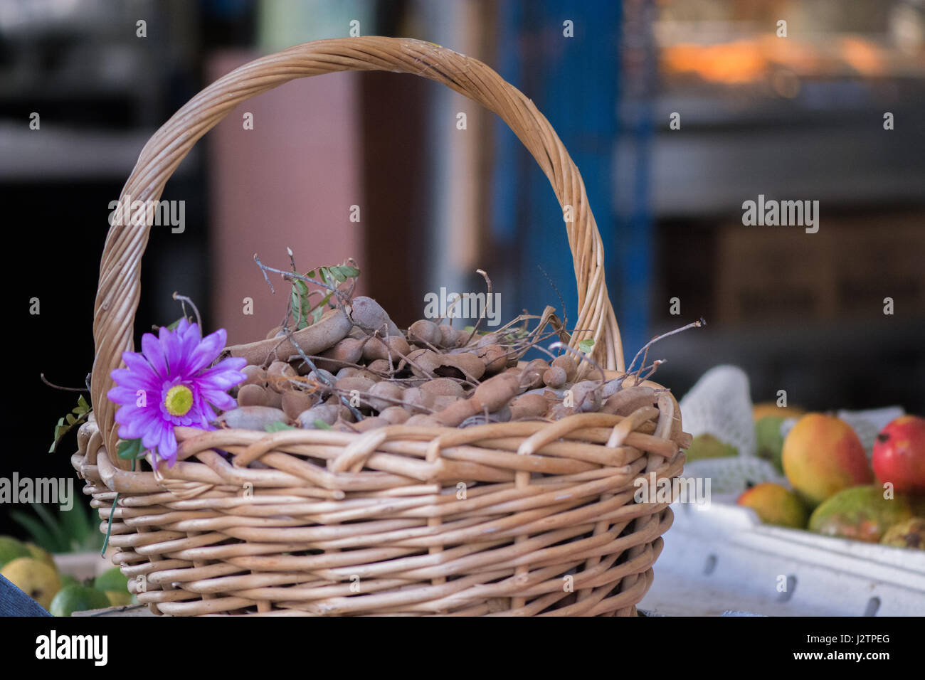 Cesto di tamarindi e un fiore viola in un mercato messicano. Foto Stock