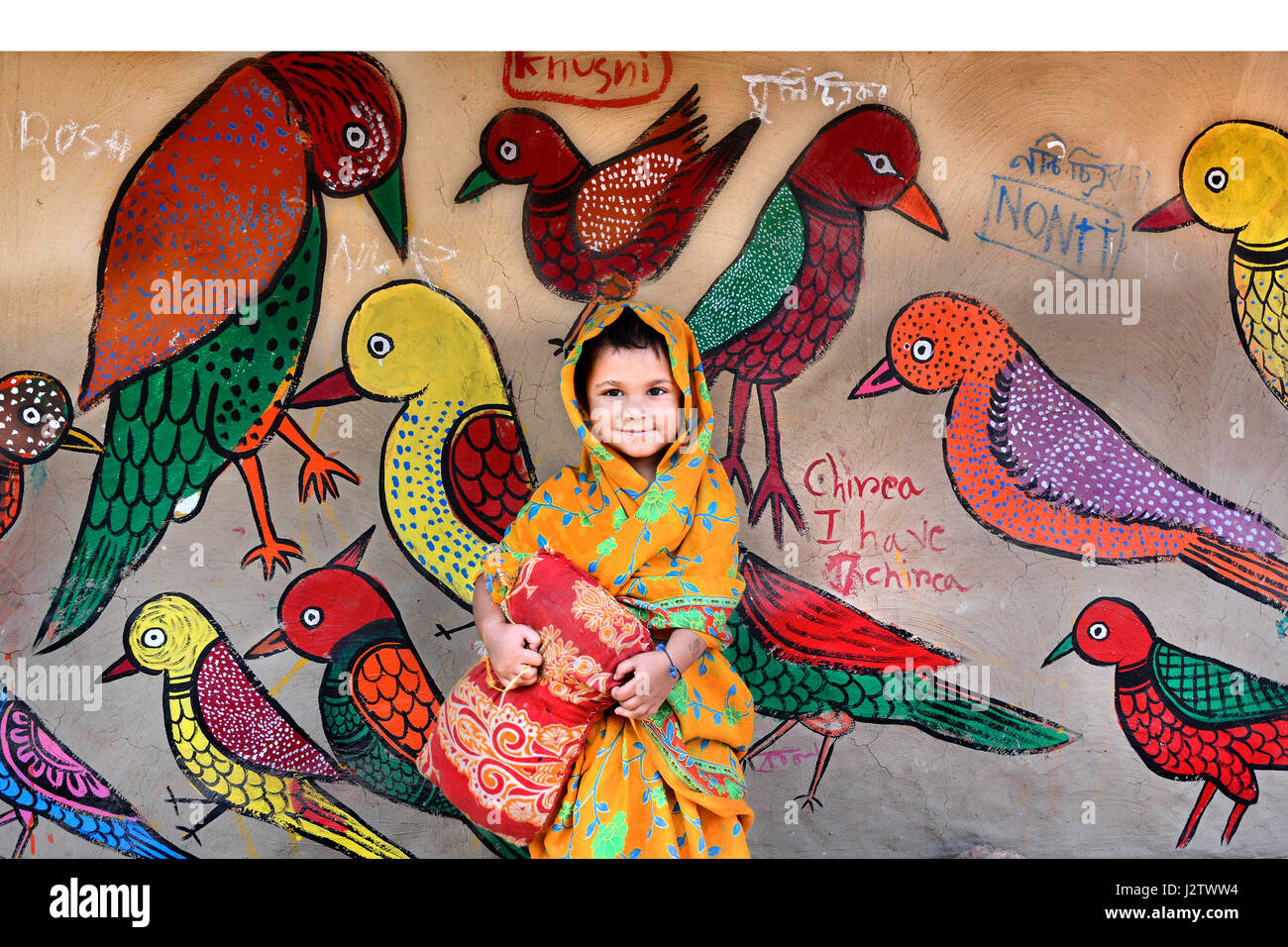 Una bambina gioca con muro dipinto di uccelli. Foto Stock