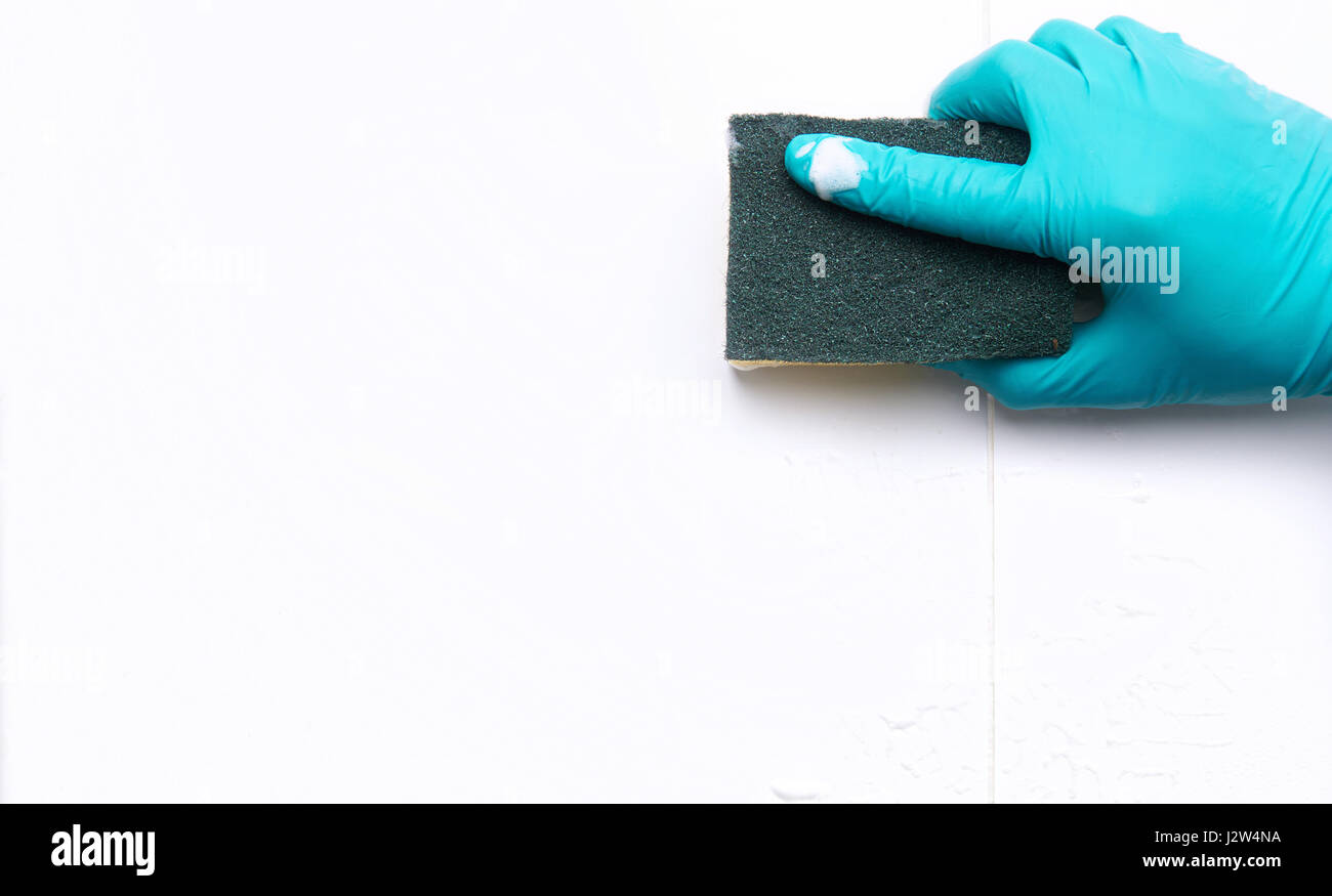 Maschio con mano la pulizia del bagno piastrelle e spazi con una spugna. Con copia spazio. Foto Stock