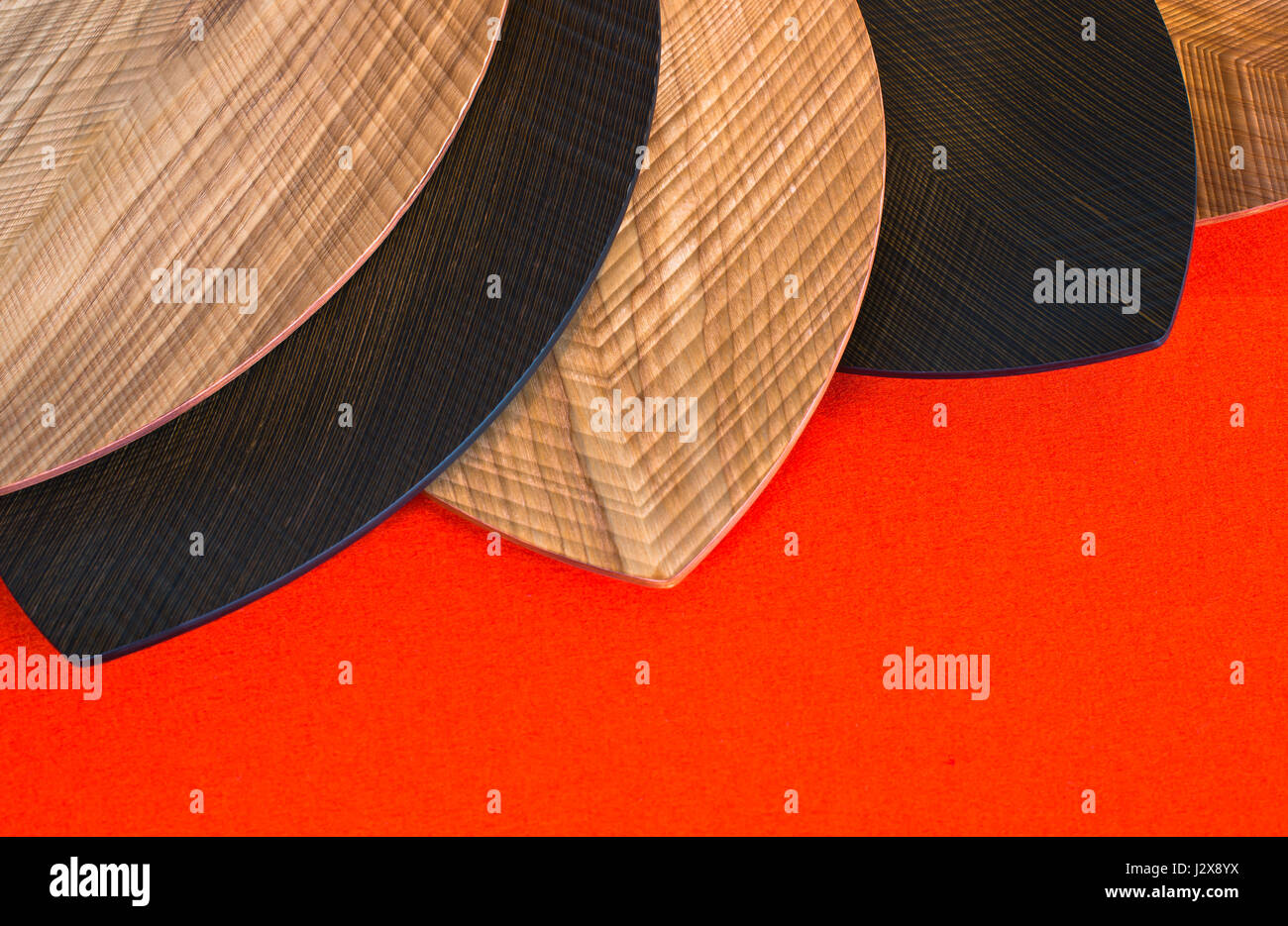 Il design moderno delle piastre di luce naturale e legno scuro in forma e consistenza delle foglie su uno sfondo di colore arancione lana naturale tabella runner Foto Stock