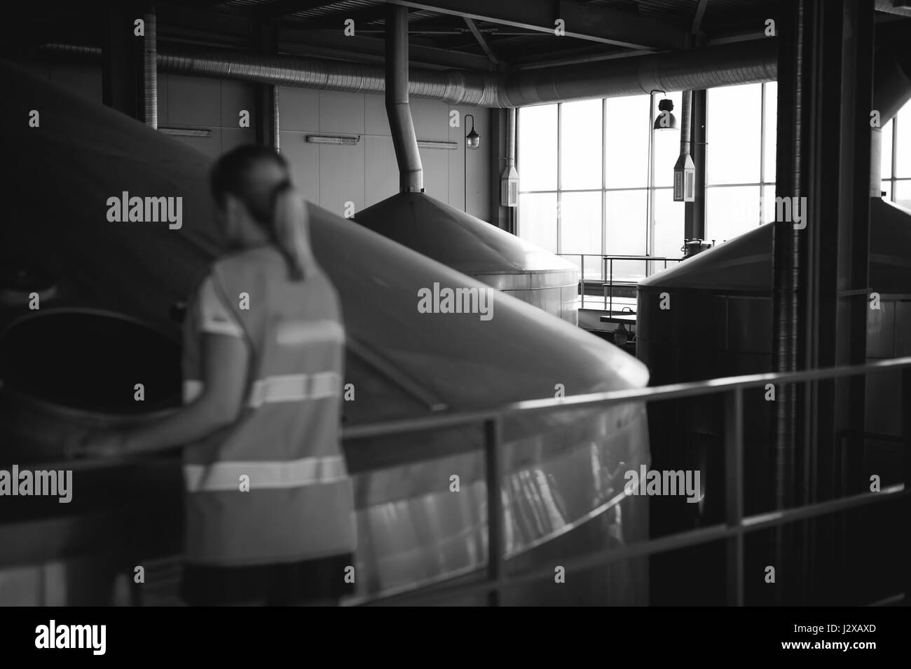 Lavoratore di sesso femminile che sulla fabbrica di birra. ritratto donna in accappatoio, permanente sulla linea di sfondo della produzione alimentare, il controllo di gestione di apparecchiature di controllo per il processo di produ Foto Stock