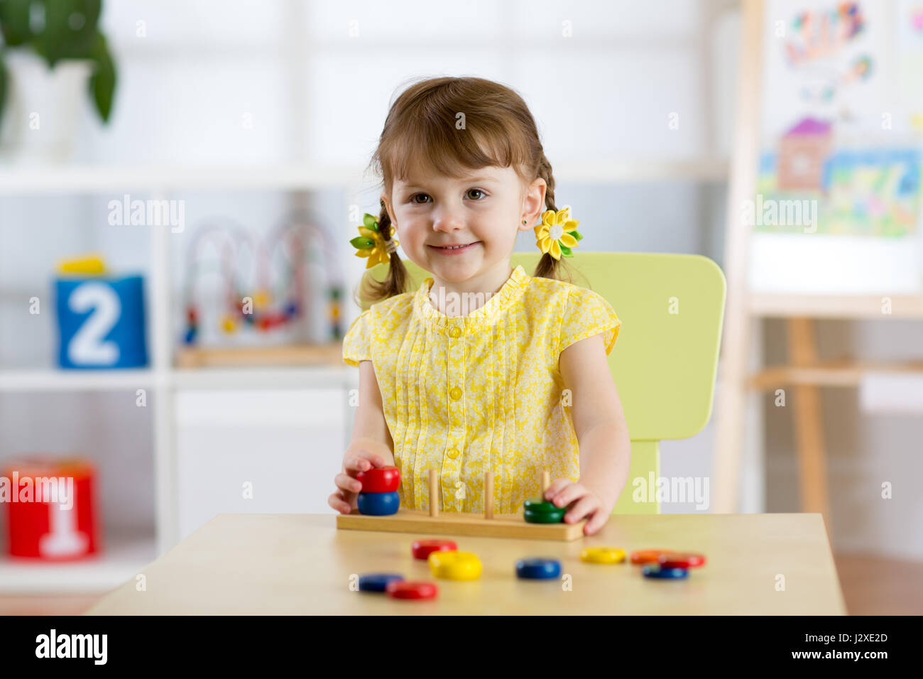 Kid ragazza che gioca con il giocattolo logico sulla scrivania in nursery room o asilo nido. Disponendo del bambino e lo smistamento di colori e dimensioni Foto Stock