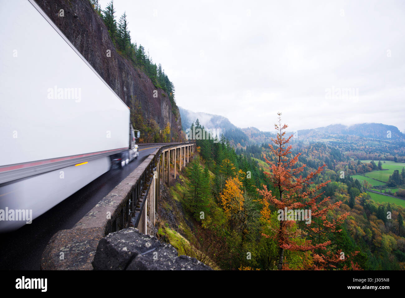 Impressionante panorama della valle del fiume Columbia Gorge nella stagione autunnale con un enorme long haul cargo semi carrello con un dry van spostamento del rimorchio Foto Stock