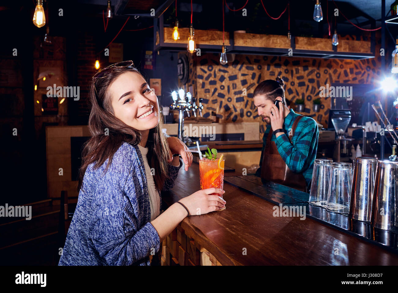 Una ragazza con cocktail di sorrisi dietro il contatore al bar Foto Stock