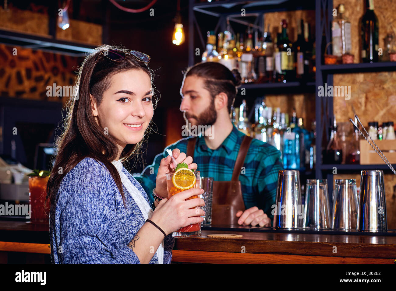 Una ragazza con cocktail di sorrisi dietro il contatore al bar Foto Stock