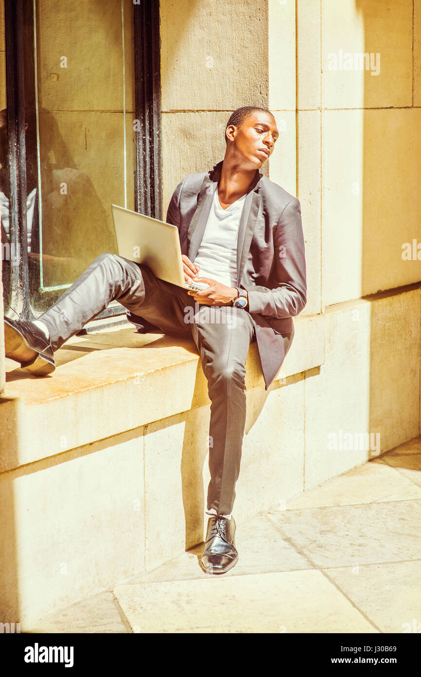 Compito Difficile. Medicazione in elegante giacca, pantaloni e scarpe di cuoio, un giovane nero studente di college è seduto contro un telaio di finestra, guardando lontano, s Foto Stock