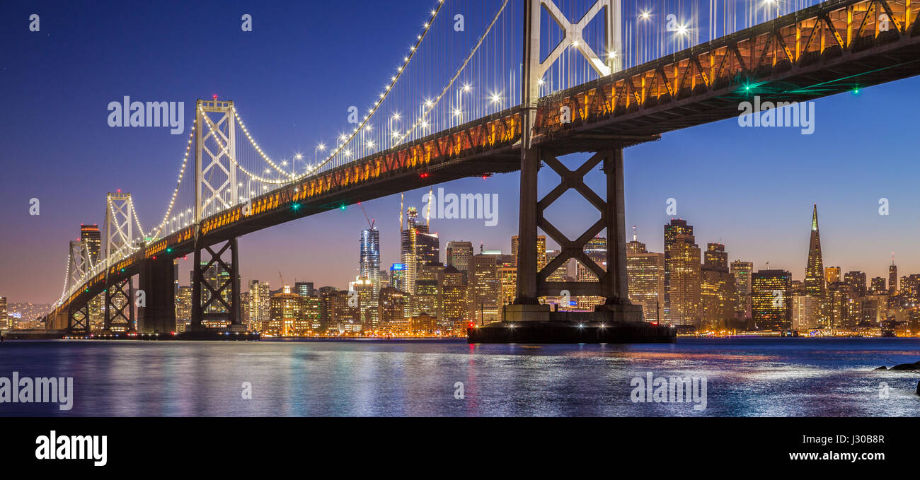 Classic vista panoramica del famoso Oakland Bay Bridge con lo skyline di San Francisco illuminata nella splendida post tramonto crepuscolo, CALIFORNIA, STATI UNITI D'AMERICA Foto Stock
