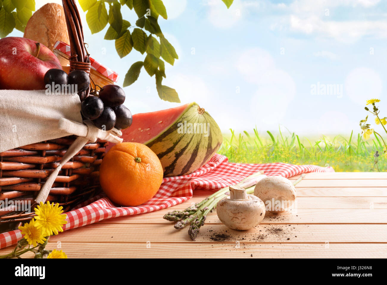 Picnic a cesto in vimini con il cibo sulla tavola di legno sulla spiaggia  con cielo blu di sfondo e sun. Il concetto di picnic. Vista frontale.  Composizione orizzontale Foto stock 