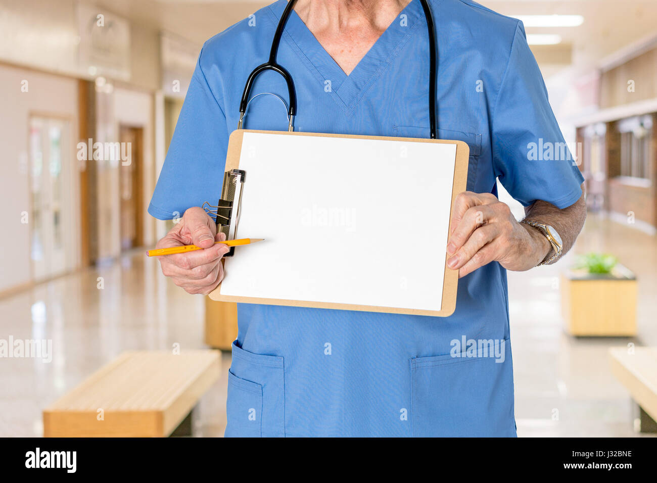 Medico con stetoscopio in medical scrubs holding negli appunti di vuoto per il messaggio di assistenza sanitaria Foto Stock