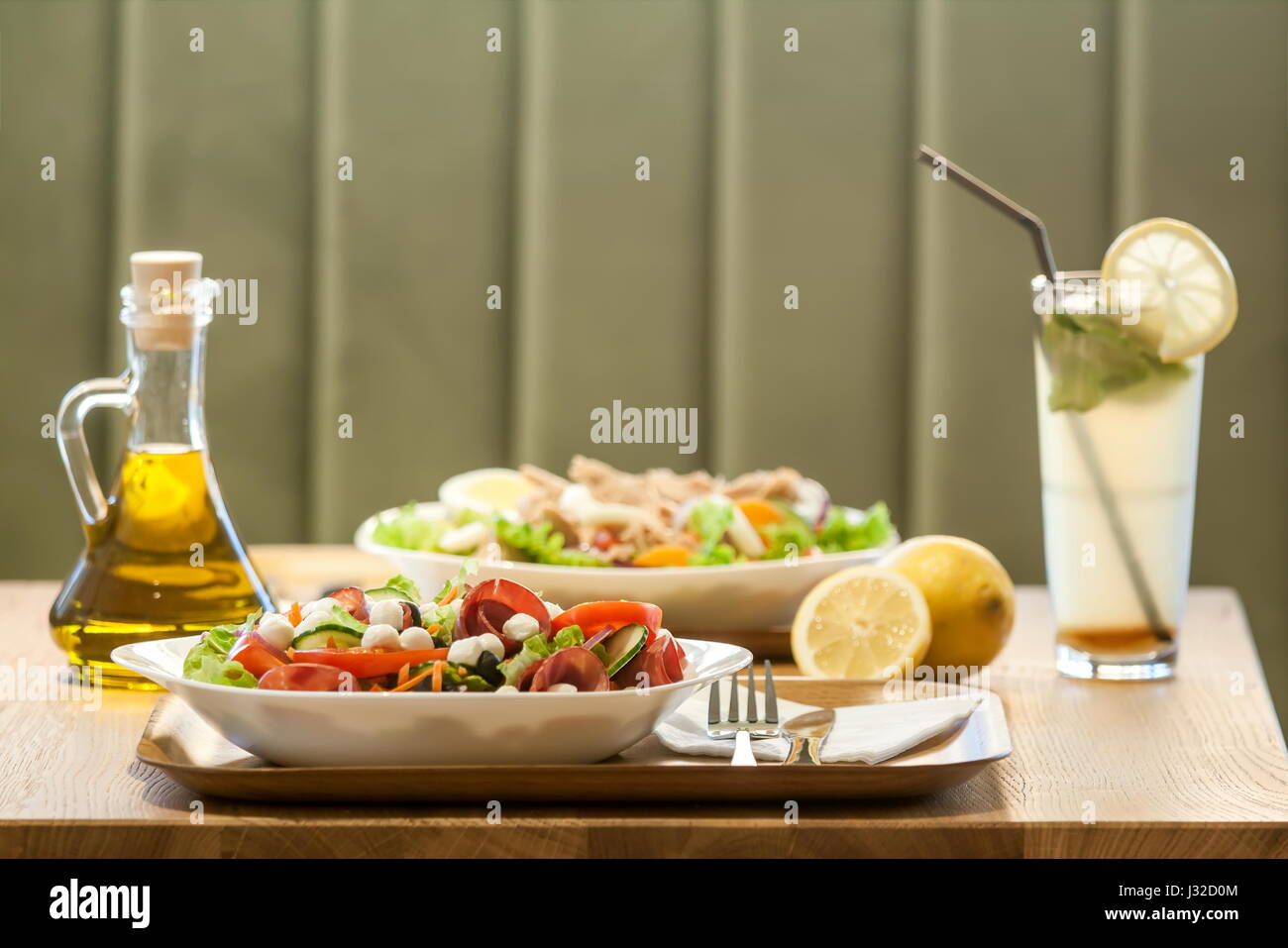 Due insalate con prosciutto, carne, pomodori, mozzarella, il succo di limone e olio di oliva Bottiglia Foto Stock