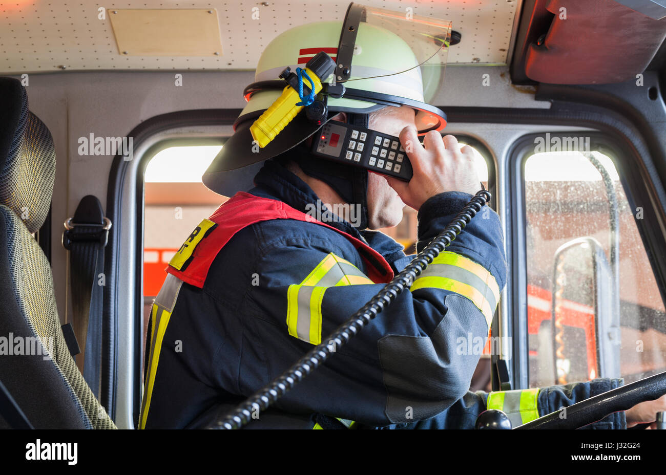 Vigile del fuoco tedesco rigidi in un camion dei pompieri in azione e utilizzato un walkie-talkie Foto Stock