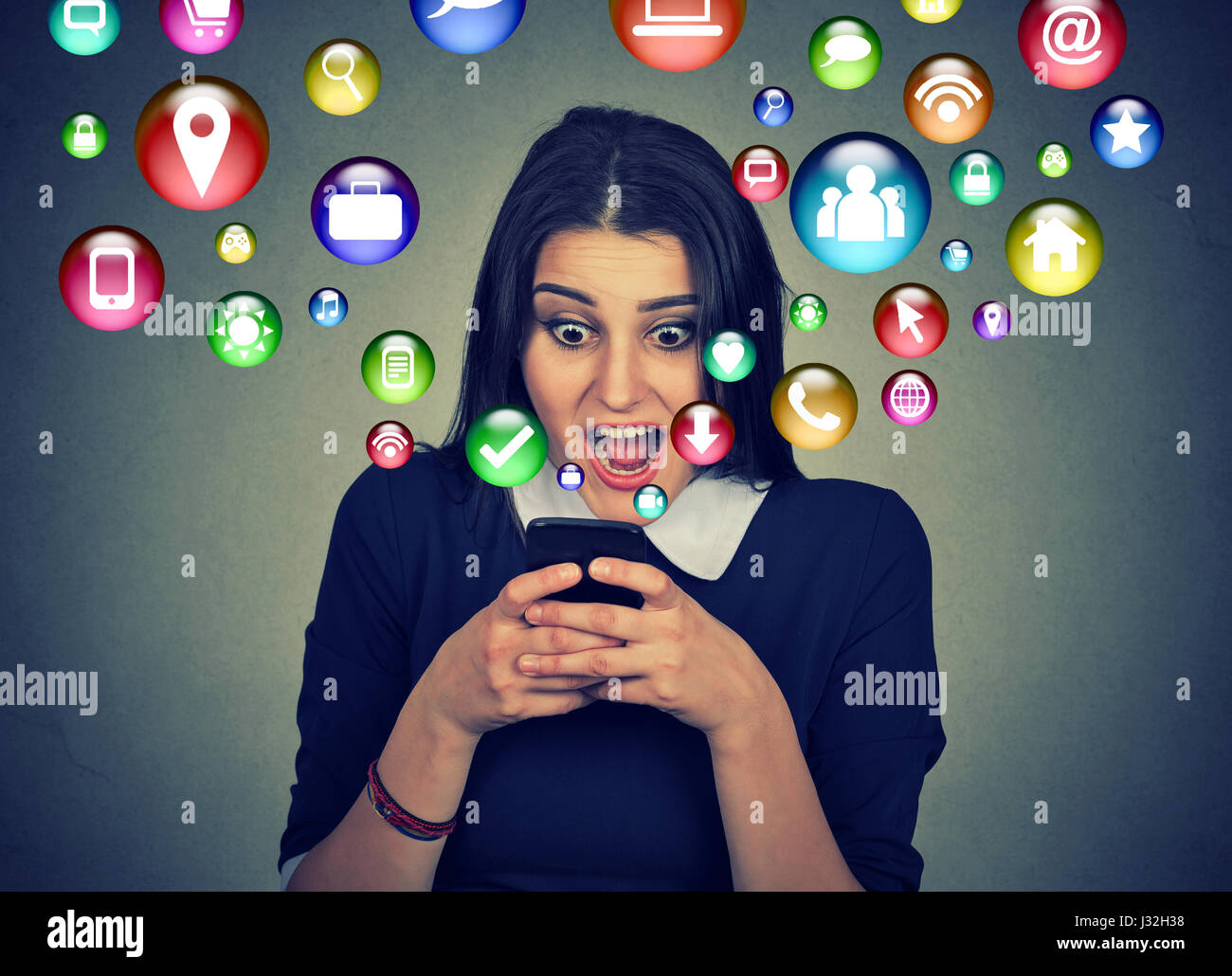 La tecnologia di comunicazione mobile high tech concetto. Closeup sorpreso giovane donna utilizzando messaggi di testo sullo smartphone con i social media simboli di applicazione ico Foto Stock