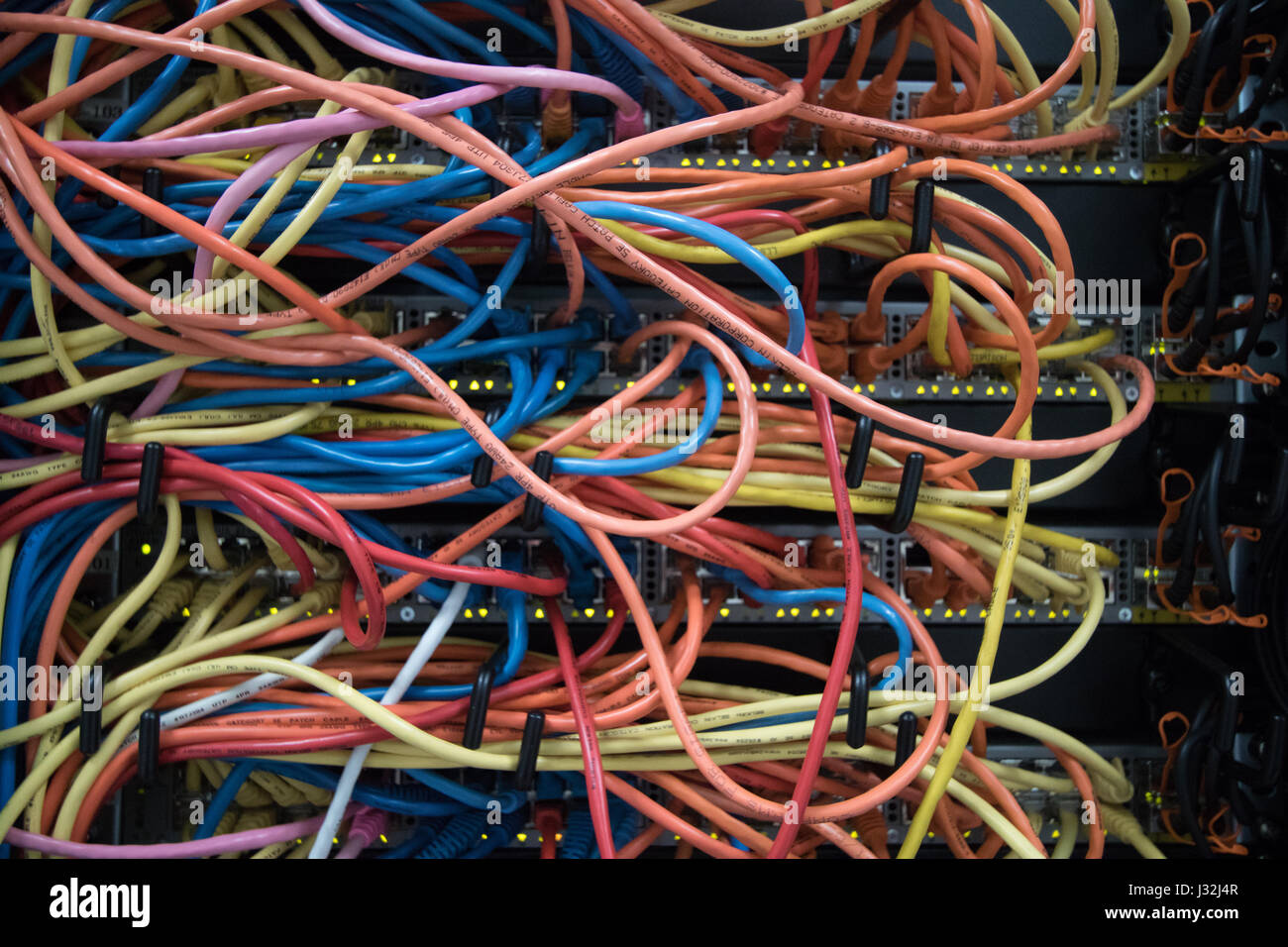 Un groviglio di cavi Ethernet collegati alla rete apparecchiature switch in  un centro dati Foto stock - Alamy