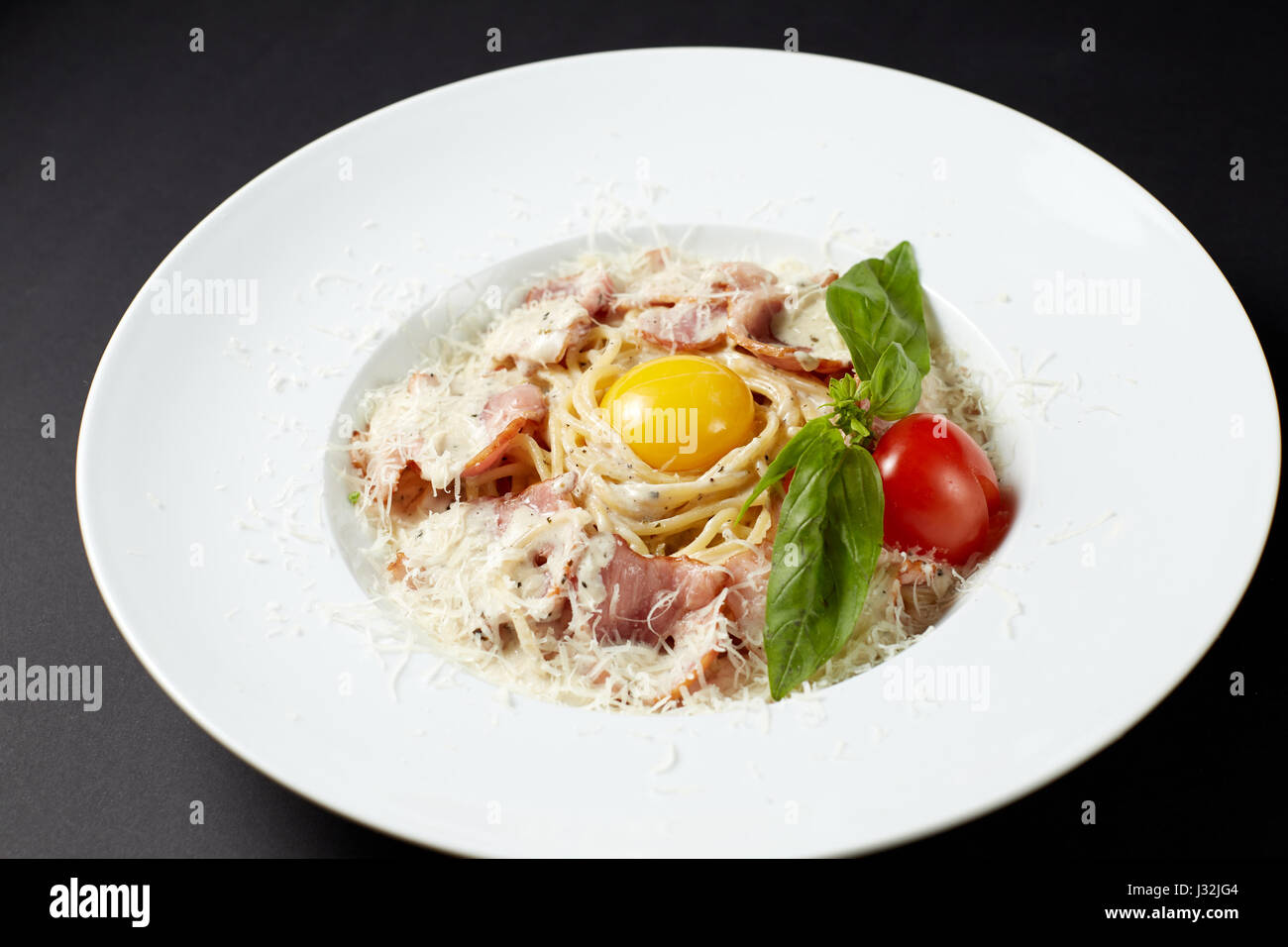 Spaghetti alla carbonara. Stile italiano. Il cibo italiano. Cucina Italiana. Studio shot sul buio o sfondo nero. Foto Stock