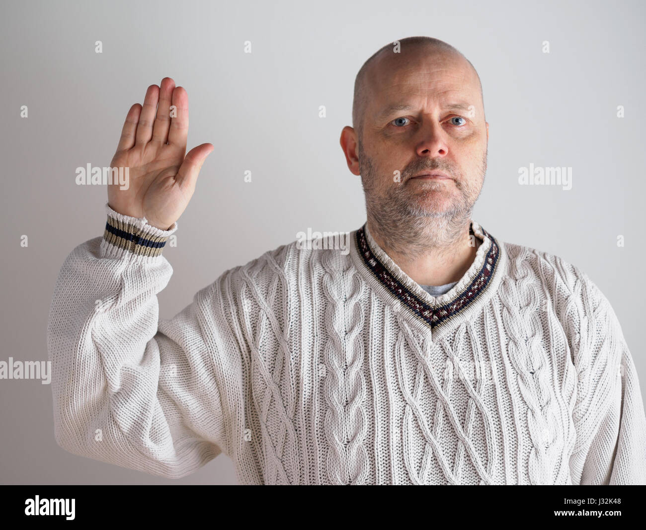 Ritratto, casual cercando maschio caucasico che indossa un maglione bianco, lato destro sollevato e guarda verso la telecamera Foto Stock