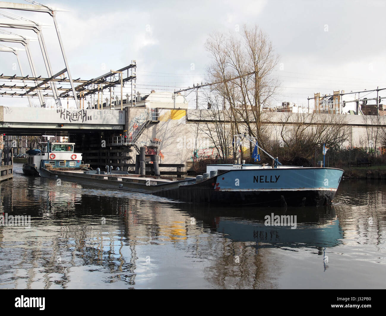 La fotografia mostra la Nelly, una nave costruita nel 1964, che passa accanto alla Willemsbrug di Rotterdam. L'immagine cattura il movimento della nave attraverso l'iconico ponte della città. Foto Stock
