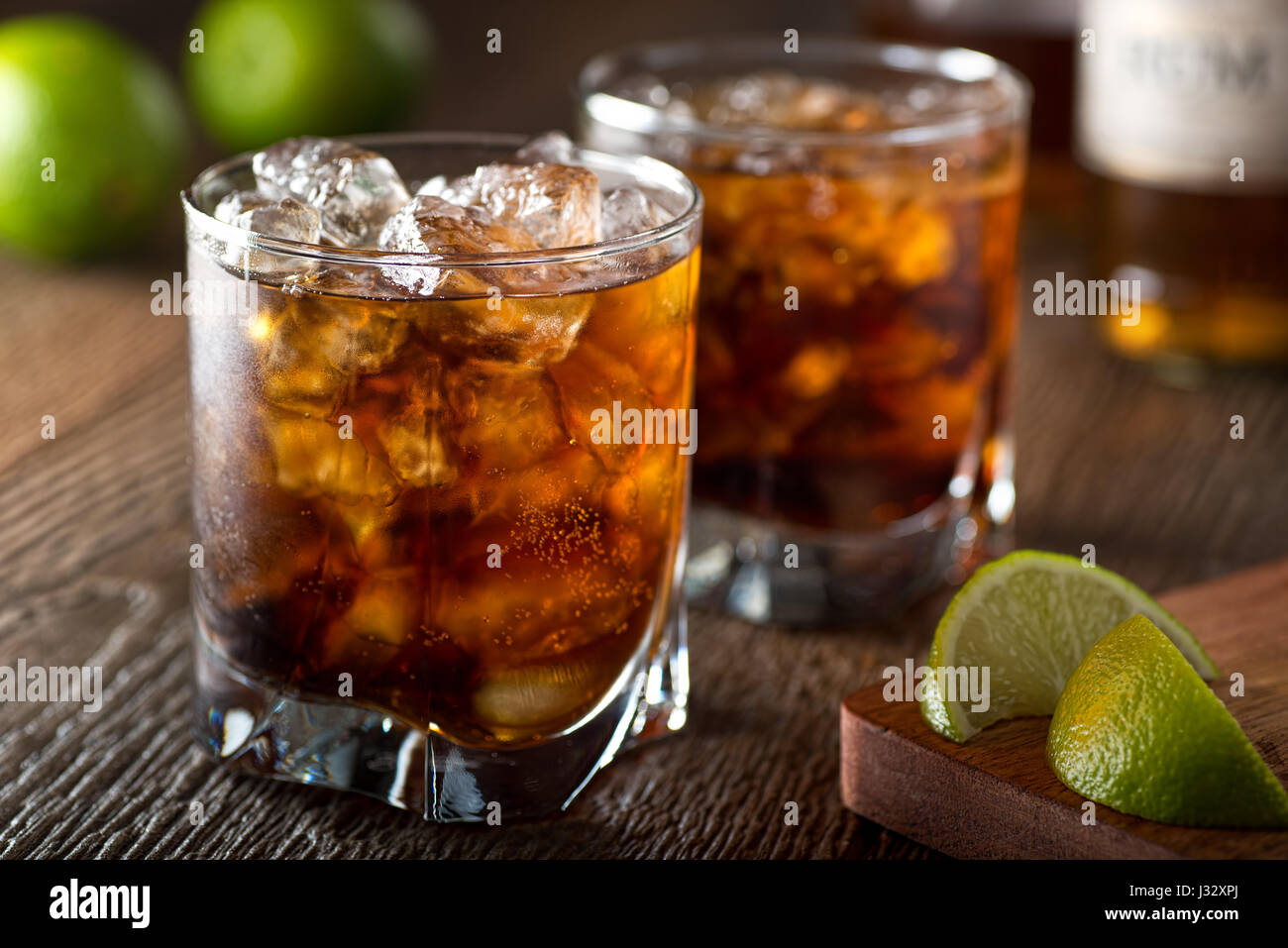 Il rum e la cola cuba libre con calce e ghiaccio su una barra di legno alto. Foto Stock