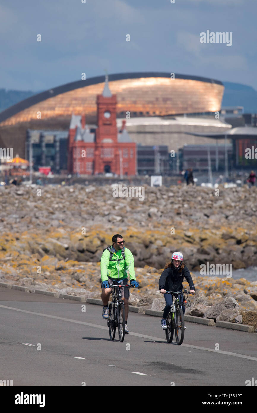 I ciclisti corsa sulla baia di Cardiff barrage durante le calde giornate di sole su le vacanze di maggio a Cardiff, nel Galles del Sud. Il met office ha avvertito di docce o Foto Stock