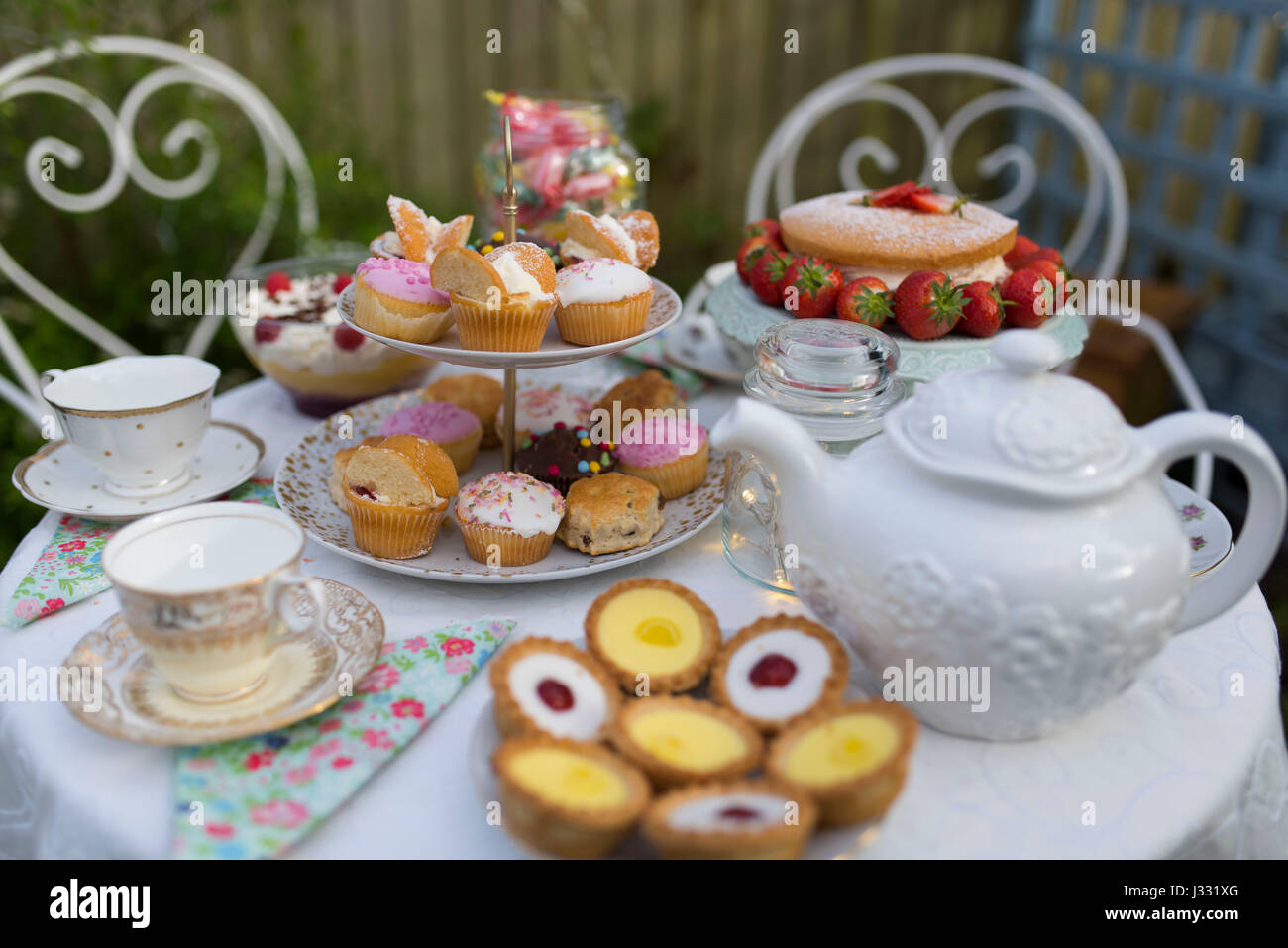 Un tavolo preparato per il tè del pomeriggio / garden party in un giardino. Foto Stock