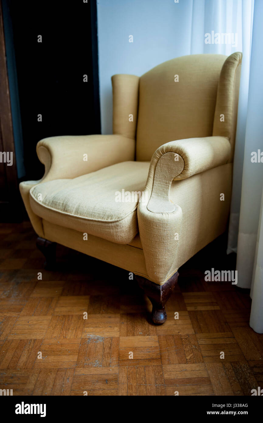 Una poltrona marrone in un vecchio appartamento con pavimento in legno Foto Stock