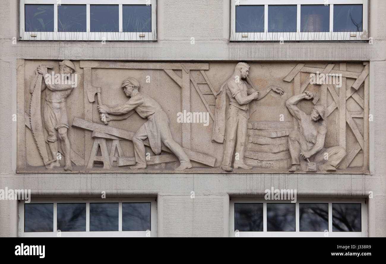 Incidente in falegnameria. Sollievo da scultore ungherese Bela Markup (1930) sull'ala nord del palazzo Art Deco di Budapest - i lavoratori del fondo di assicurazione in Budapest, Ungheria. L'edificio, ora utilizzato come sede dell'Assicurazione Sociale Nazionale Centro (OTI), è stato progettato da architetti ungheresi Komor Marcell e Jakab Dezso e costruito nel 1913. L'ala nord è stato aggiunto dall'architetto Aladar Sos nel 1930-1931. Foto Stock