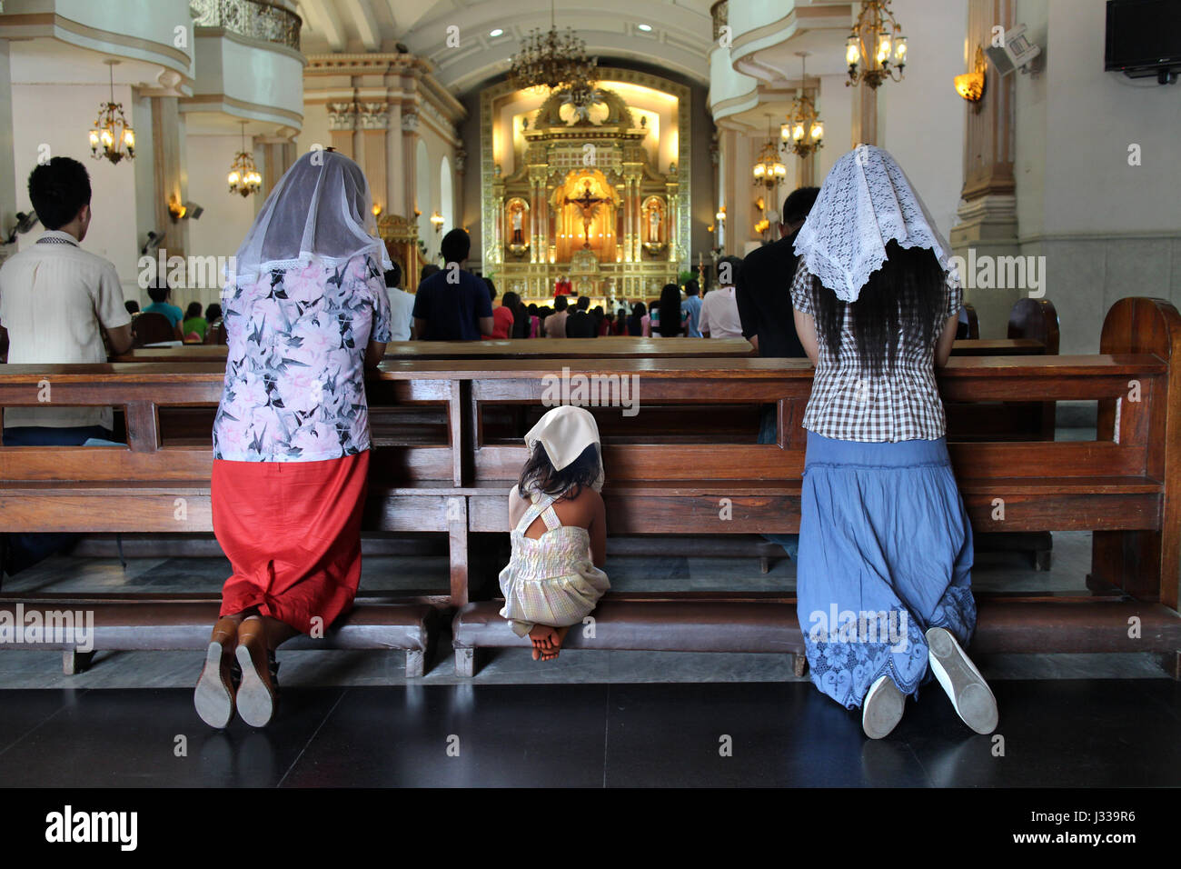 Donna e bambino inginocchiarsi e pregare, Cebu Metropolitan Cathedral, Filippine, Asia Foto Stock