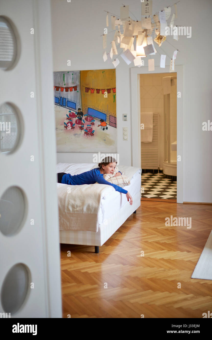 Donna sul letto in suite Boesendorf n. 27, con pianoforte, Altstadt Vienna Hotel, Kirchengasse 41, settimo distretto, Vienna, Austria Foto Stock