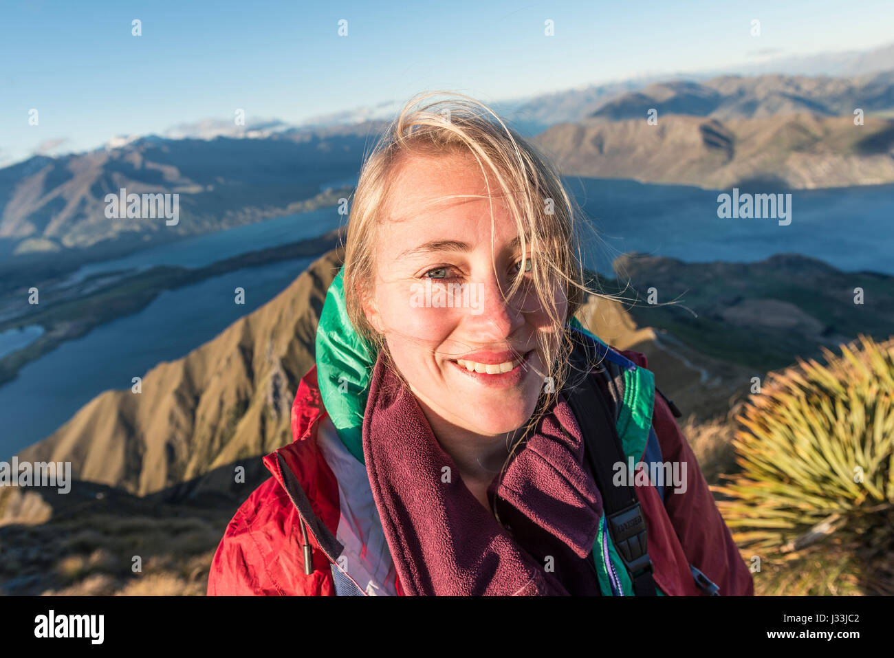 Escursionista ridere per fotocamera, Roys picco, il lago Wanaka, Alpi del Sud, regione di Otago e Southland, Nuova Zelanda Foto Stock