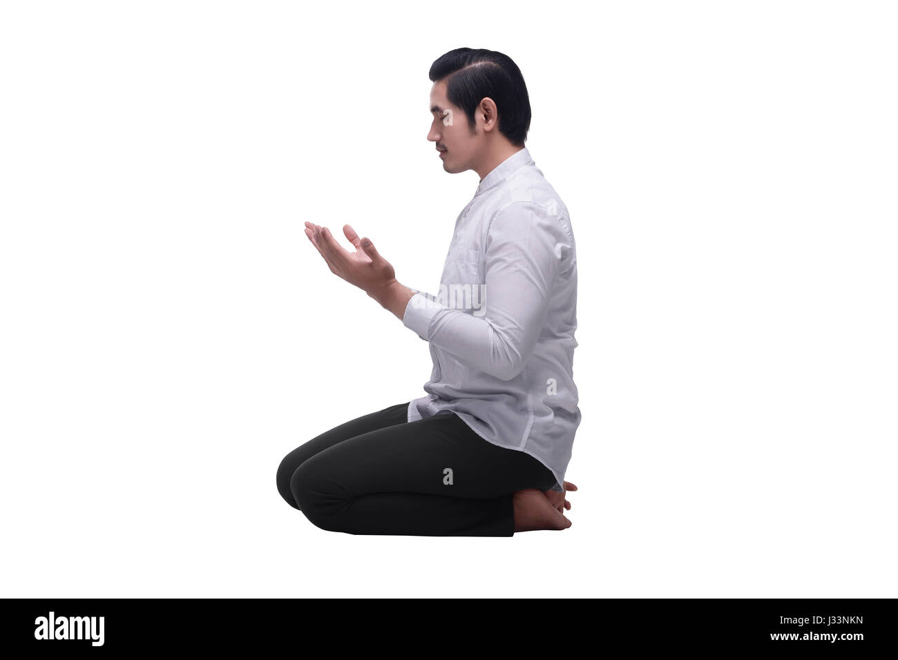 Religiosi musulmani asiatici uomo seduto mentre pregava isolate su sfondo bianco Foto Stock