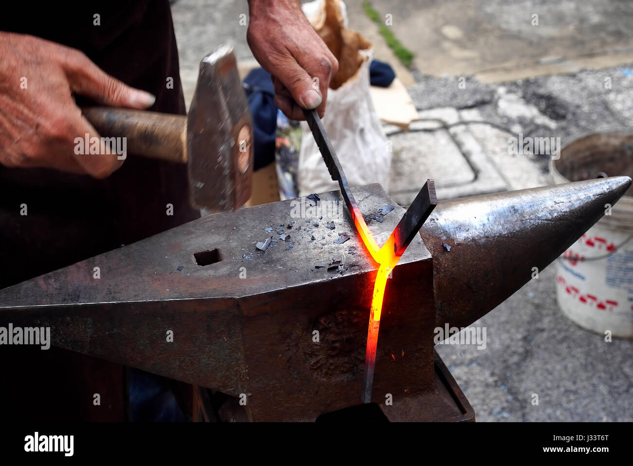 Colpisce un pezzo di ferro caldo su un' incudine con il martello. Foto Stock
