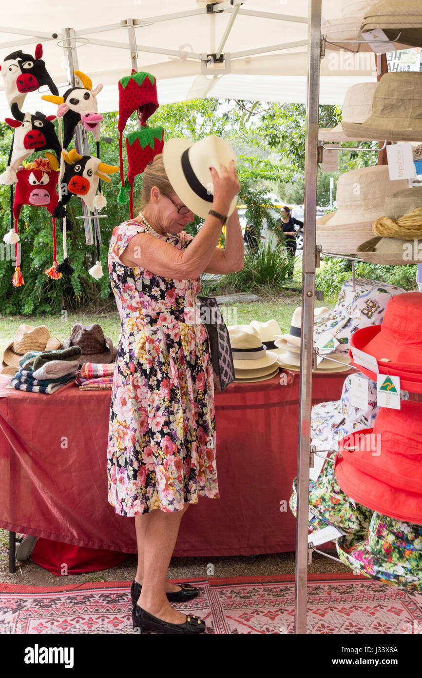 Senior donna cercando su un cappello a mercati Eumundi, Queensland, Australia Foto Stock