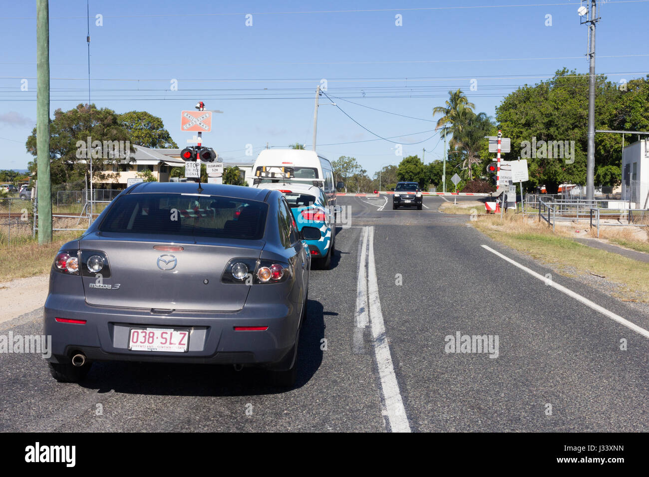 Il traffico in attesa alla barriera di passaggio a livello per un treno per passare, Queensland, Australia Foto Stock