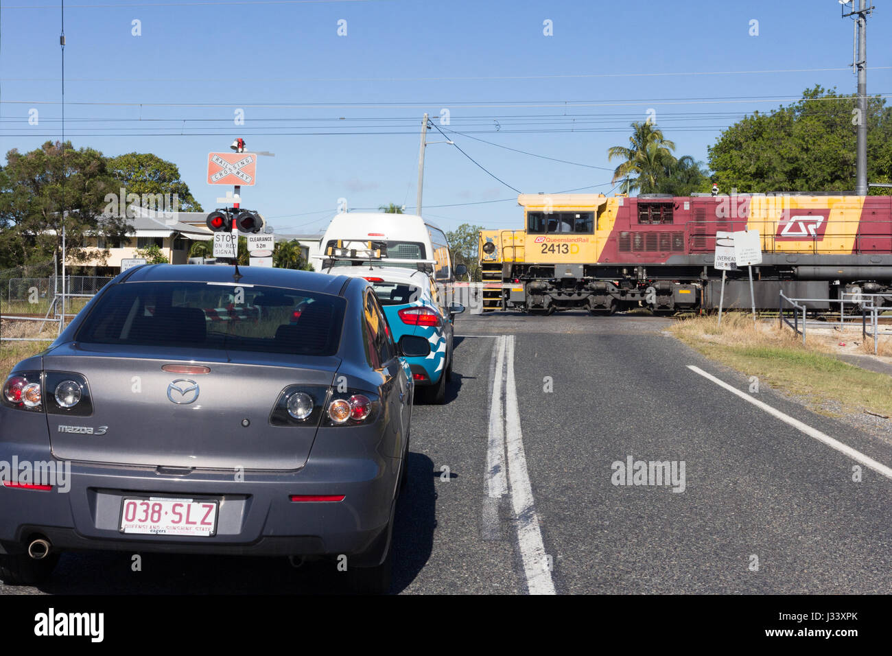 Il traffico in attesa alla barriera di passaggio a livello per un treno per passare, Queensland, Australia Foto Stock