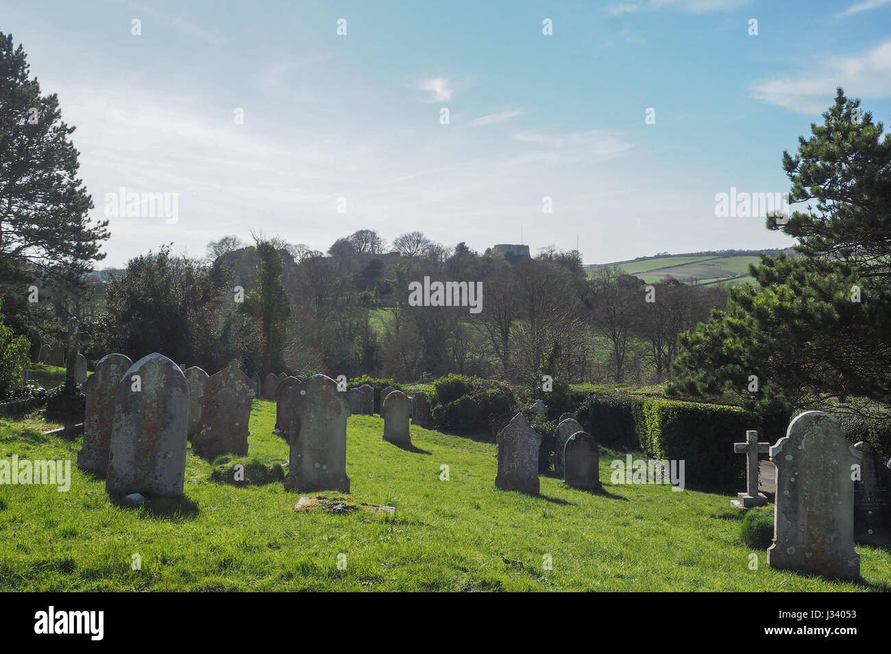 Il castello di Carisbrooke dal Monte gioia Cimitero Cimitero incorniciata dagli alberi retroilluminato con lapidi le lapidi sul pendio della luce della sera giornata soleggiata nube di luce Foto Stock