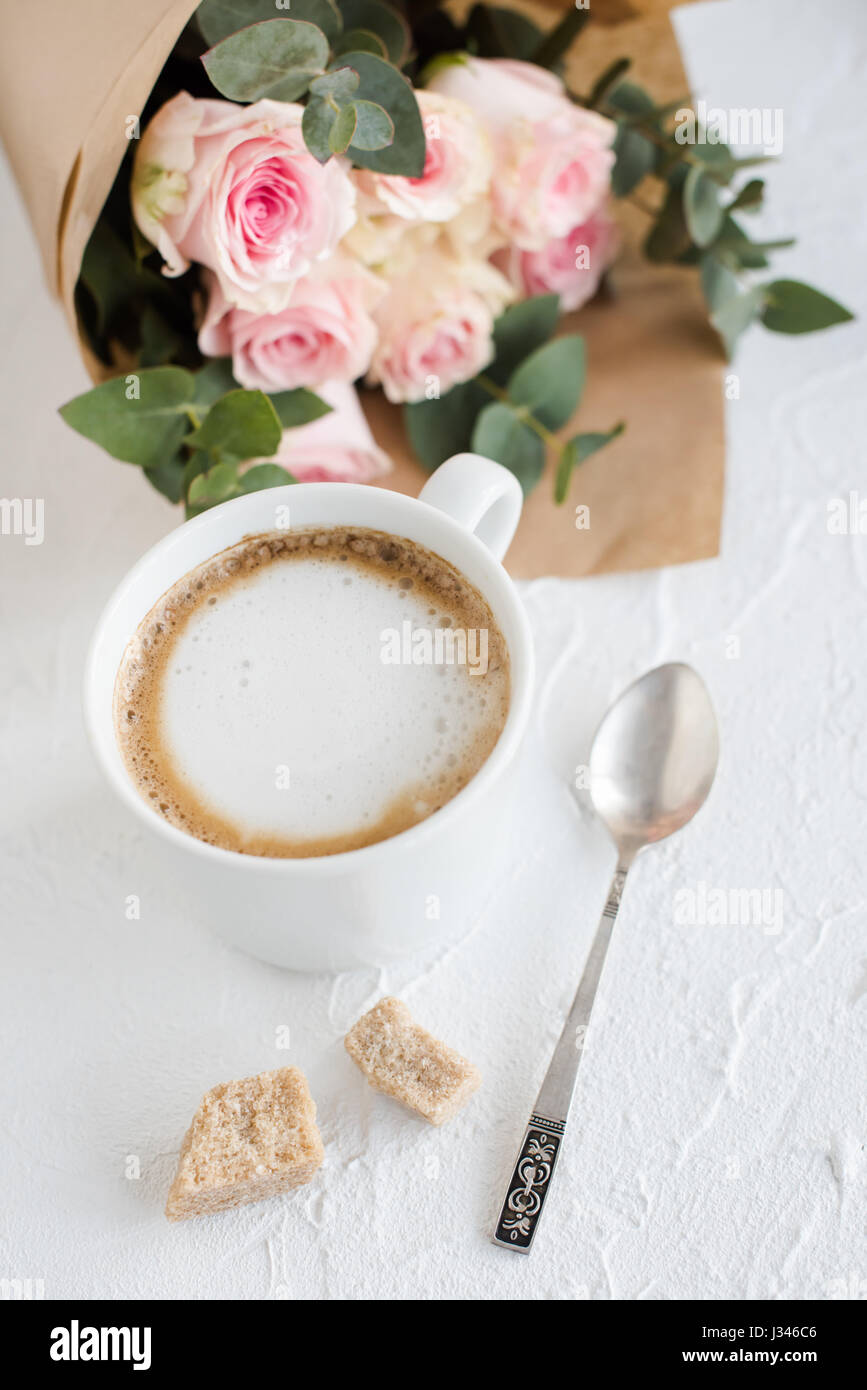 Romantico sfondo femminile con caffè e rose su bianco a trama il piano portapaziente, elegante flatlay luce Foto Stock