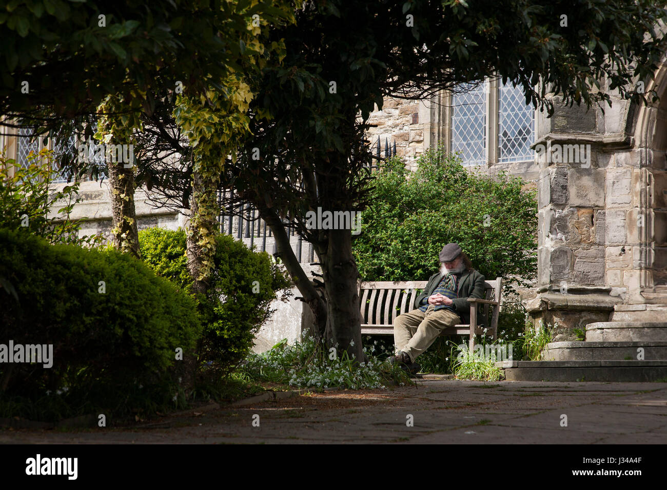 L'uomo assume un pisolino pomeridiano al di fuori di San Clemente chiesa in Hastings Old town. Foto Stock