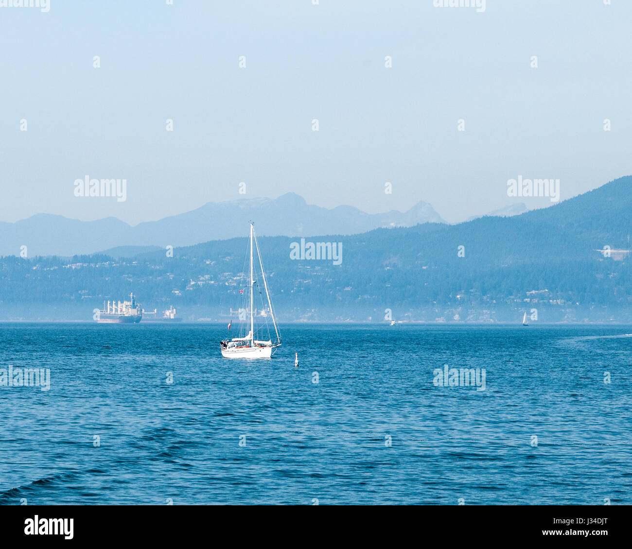 In una giornata frizzante, barche private e navi commerciali aspettano nella English Bay fuori Vancouver, British Columbia. Vista da Vanier Park. Foto Stock