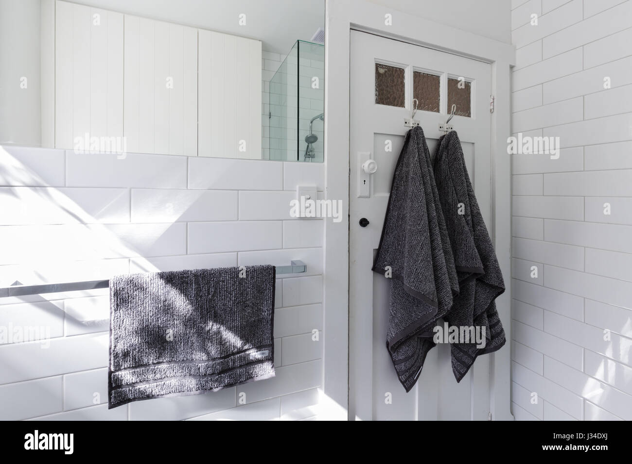 Asciugamani di lusso sulla porta ganci in moderno bagno bianco con pattern di mattoni alla metropolitana di piastrelle Foto Stock